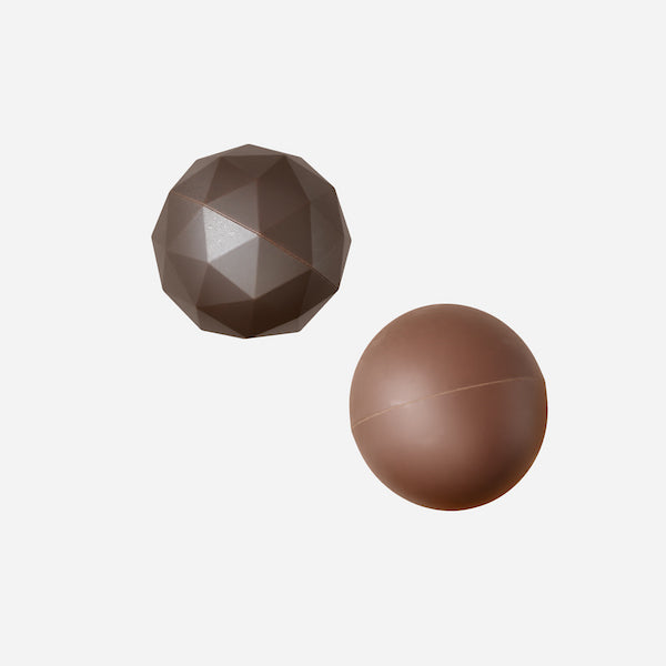 Zoku | Bomb Chocolate Mold: Two brown spheres, one faceted, one smooth, illustrating the mold's ability to create textured and smooth chocolate bombs.