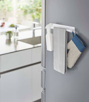 Yamazaki Home - Magnetic Kitchen Towel Hanger - Steel: White, holds a spray bottle, towel, and oven mitt on a refrigerator side, perfect for organizing kitchen essentials.