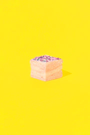 Malvi Mallow - Cotton Candy 4-Pack Marshmallows: A single pinkish-cream cube with sprinkles on yellow background, highlighting its airy texture and sweet cotton candy flavor.