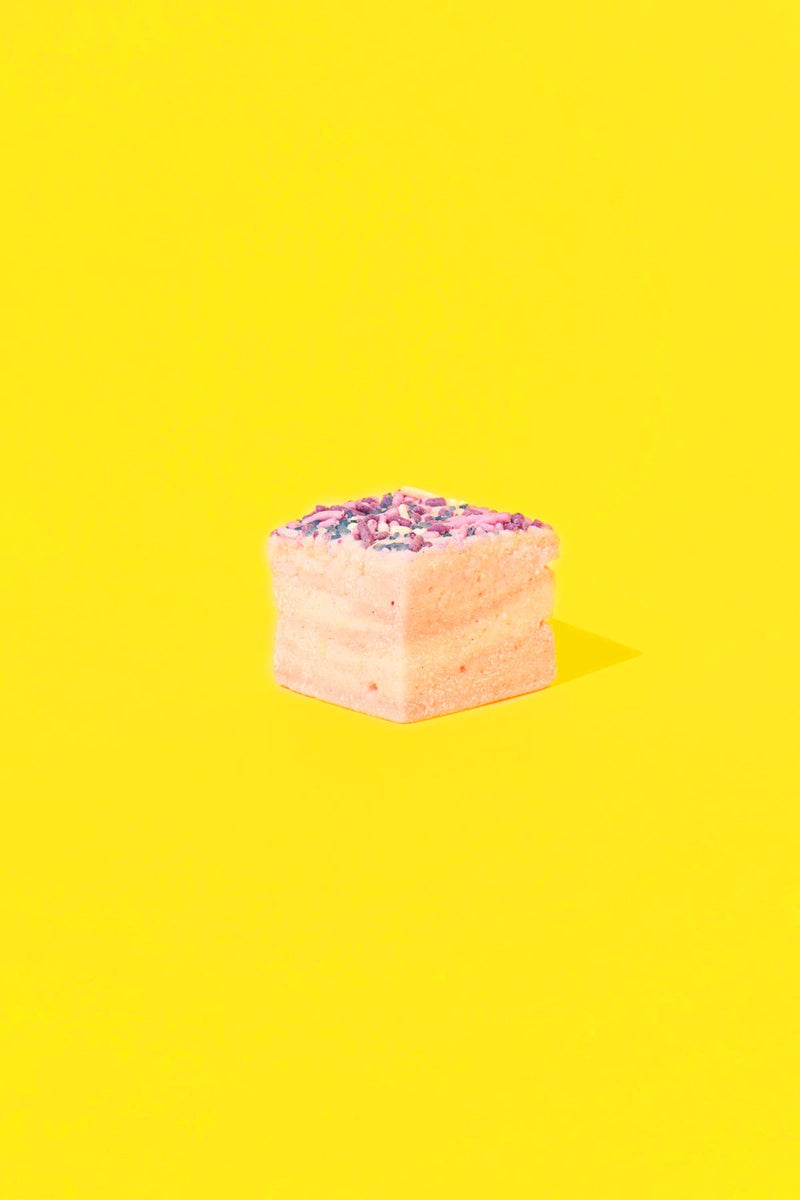 Malvi Mallow - Cotton Candy 4-Pack Marshmallows: A single pinkish-cream cube with sprinkles on yellow background, highlighting its airy texture and sweet cotton candy flavor.