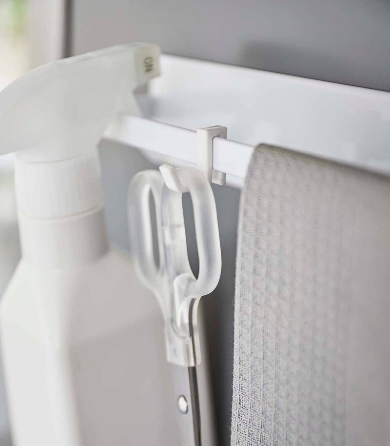 Yamazaki Home - Magnetic Kitchen Towel Hanger in white, displaying a clip-on hook system holding scissors and a cloth for efficient kitchen organization.