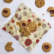 Bee's Wrap - Assorted 3 Pack - Meadow Magic, Plant-Based Wax, displayed with assorted oatmeal cookies, showcasing reusable, vegan wraps for sustainable food storage.