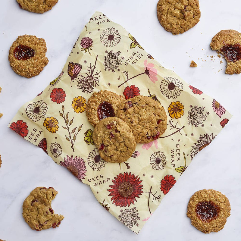 Bee's Wrap - Assorted 3 Pack - Meadow Magic, Plant-Based Wax, displayed with assorted oatmeal cookies, showcasing reusable, vegan wraps for sustainable food storage.