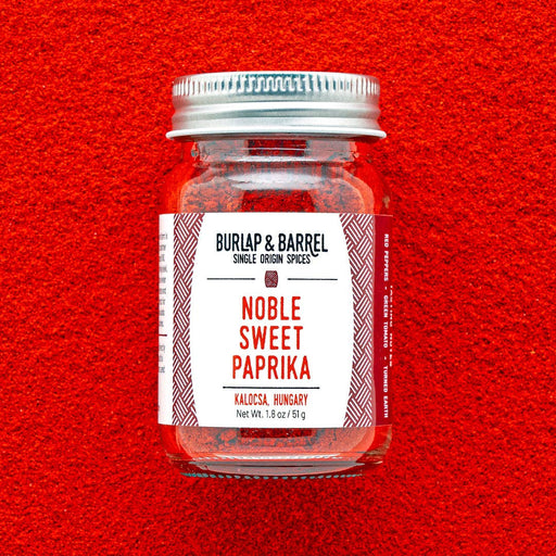 Burlap & Barrel - Noble Sweet Paprika - Single Origin Spice & Seasoning: 1.8 oz glass jar on paprika-covered surface, showcasing vibrant Hungarian spice from Kalocsa.