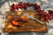 Wüsthof Amici 5 Serrated Utility Knife on a cutting board beside a sausage, exemplifying Athens Cooks' premium kitchen tools.
