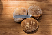 Wüsthof | Amici 9 Double Serrated Bread Knife beside a sliced loaf, showcasing its precision cutting on a wooden surface.
