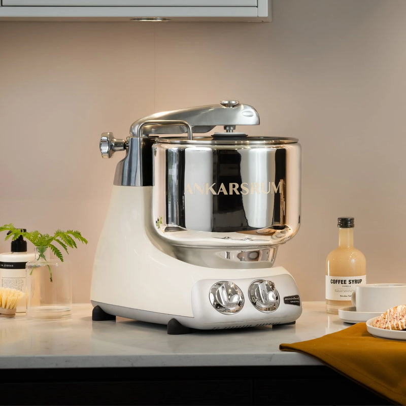 Ankarsrum stand mixer in a cozy kitchen setting, paired with greenery, coffee syrup, and a pastry, exemplifying Athens Cooks' curated kitchen elegance.