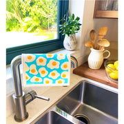Bespoke Provisions - Eggs Swedish Dishcloth displayed on a kitchen sink, with nearby utensils and a bowl of lemons.