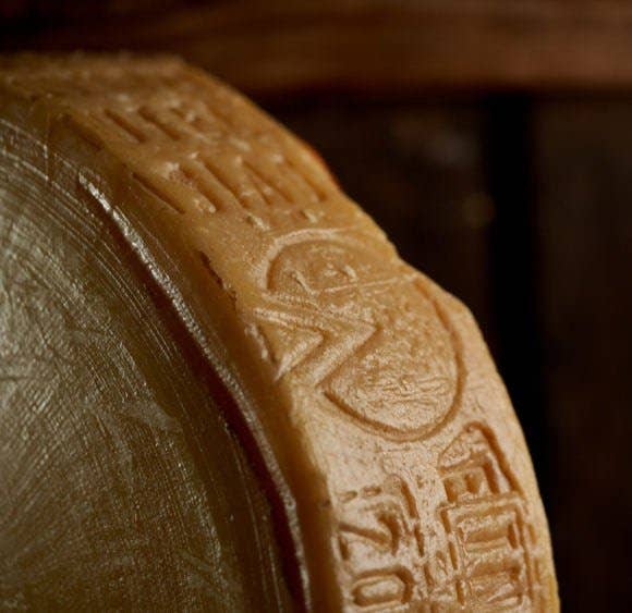 Nicola's Marketplace - Asiago D’Allevo DOP Mitica® cheese, 7 ounces: Aged Italian cheese wheel edge, golden rind with embossed markings, from Veneto, Italy, semi-firm texture.