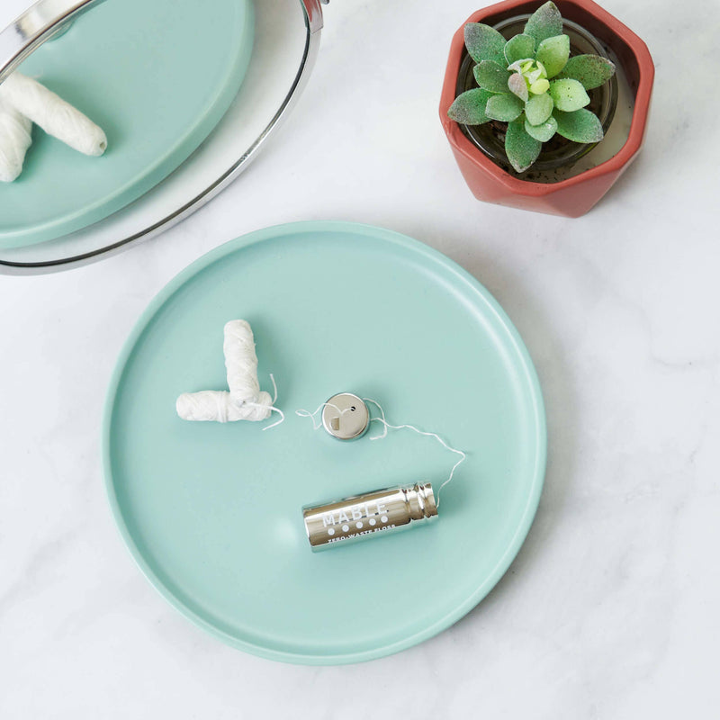MABLE - Stainless Steel Floss Container with silk floss on a teal tray, alongside tampons; embodies zero-waste dental care, ideal for eco-conscious kitchen enthusiasts.