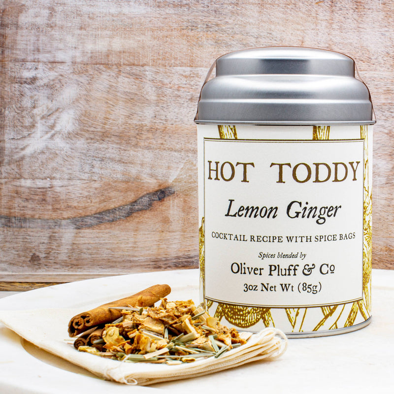 Oliver Pluff & Company - Lemon Ginger Hot Toddy Kit featuring a metal canister, dried botanicals, and spices, perfect for crafting a soothing winter drink.
