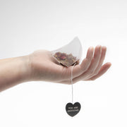 Hand holding a pyramid-shaped Big Heart Tea Co. - Rosy & Bright tea bag, featuring a heart-shaped tag reading “YOU ARE AWESOME,” against a plain white background.