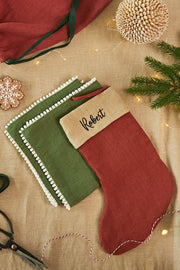 MagicLinen - Embroidered Christmas Stockings, featuring Robert in black, displayed in a festive craft scene with holiday decor, showcasing customizable, eco-friendly design.