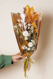 Idlewild Floral Co. - Golden Fall Market Bouquet, a hand-held dried floral arrangement featuring cream-white blooms and golden foliage, wrapped in cellophane and craft paper with a velvet ribbon.