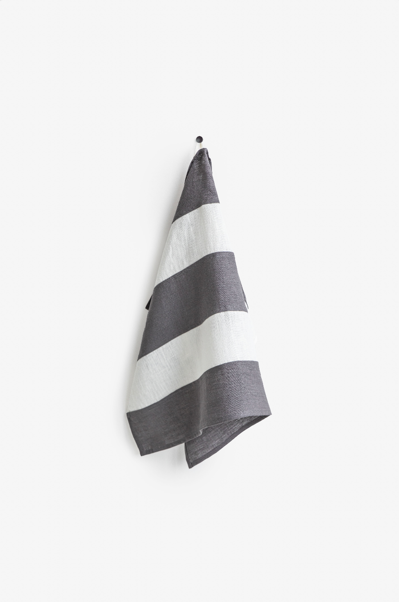 Striped linen tea towel hanging on a hook, showcasing its loop feature. Part of a zero-waste initiative, ideal for stylish, eco-friendly kitchen use.