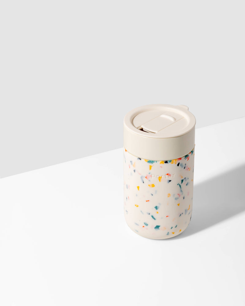 W&P Ceramic Reusable Coffee Mug 16oz: Charcoal, featuring a white ceramic body with a colorful terrazzo-patterned silicone sleeve and a secure white lid for spill-free sipping.