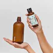 Hands holding Davids Hydroxi™ fresh breath mouthwash: one reusable 16oz bottle and one 4oz refill concentrate, featuring natural mint blend for oral health.