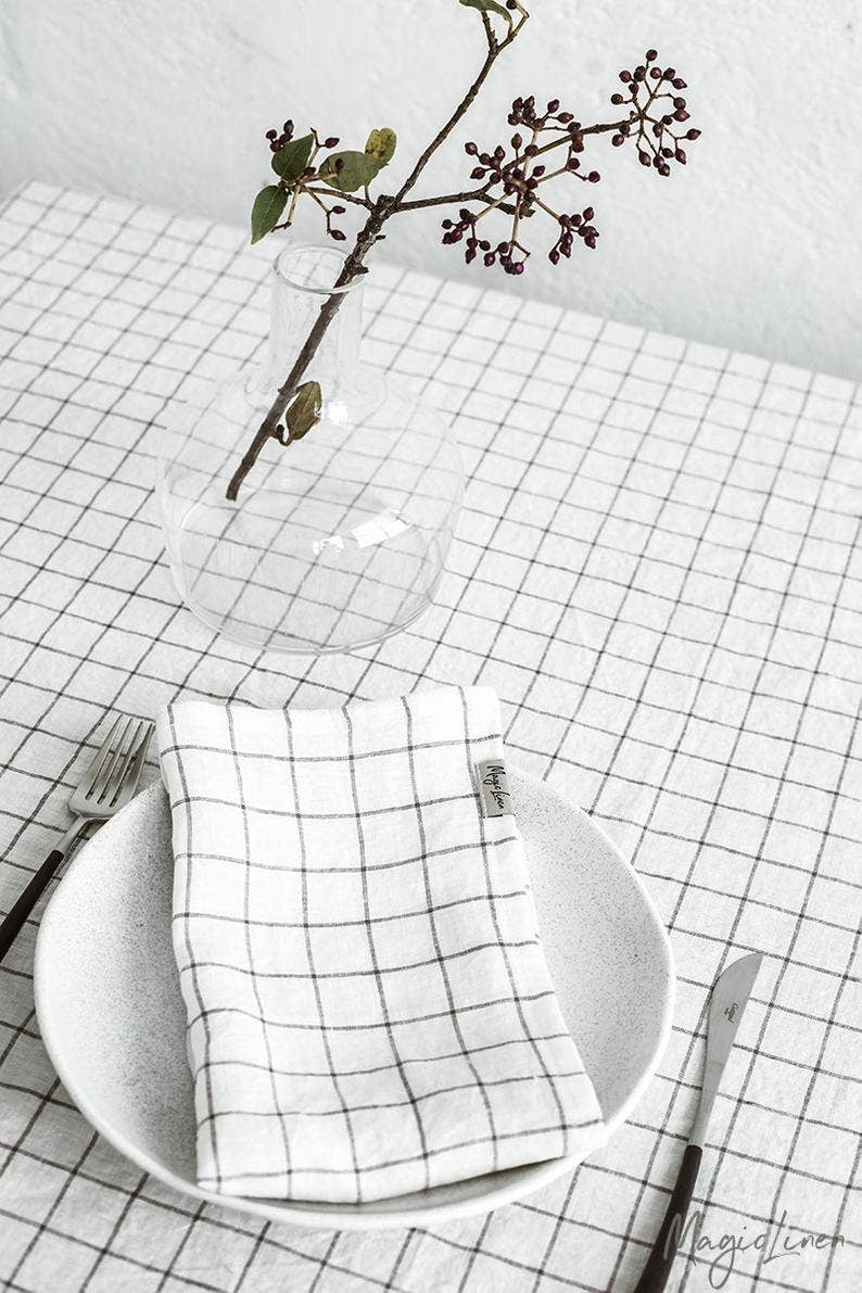 Set of 2 linen napkins on a table, featuring a plate with a fork and a decorative branch in a glass vase, emphasizing table decor.