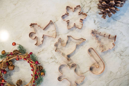 Galley and Fen - Christmas Cookie Cutters - Set of 6 on marble surface, featuring festive metal shapes and a decorative holiday wreath nearby.