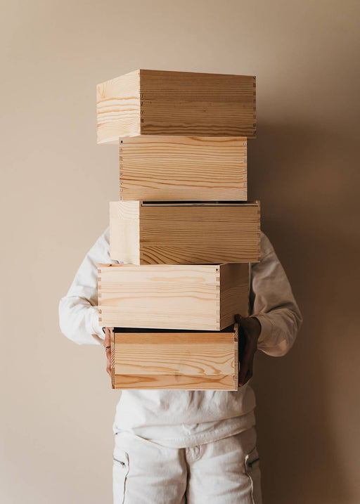 Person holding five stacked Giften Market - Wooden Gift Box Luxury Pine Keepsake with Lid - 10x10x5, showcasing elegant craftsmanship and natural pine grain.