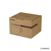 HARIO USA - HARIO Colors Glass Stackable Mug, 300ml: Grey, displayed in a plain brown cardboard box marked “HARIO COLORS” and “STACK MUG CUP,” designed for efficient storage.