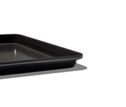 Great Jones | Holy Sheet - Pepper: A close-up of the black, nonstick half-sized sheet pan, ideal for seamless cooking and easy cleanup.