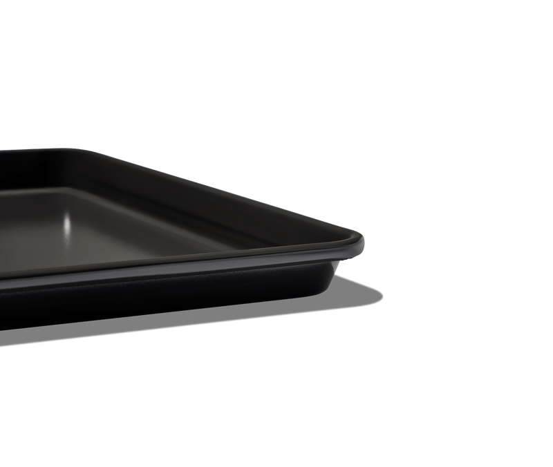 Great Jones | Holy Sheet - Pepper: A close-up of the black, nonstick half-sized sheet pan, ideal for seamless cooking and easy cleanup.