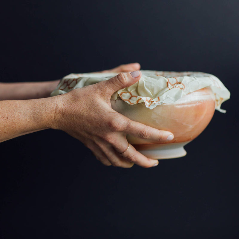 Bee's Wrap - Large 3 Pack Wraps being held, displaying its use for covering bowls, perfect for preserving kitchen items sustainably.