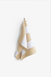 Striped linen tea towel hanging on a hook, showcasing its loop for easy storage. Part of the zero-waste program, emphasizing durability and absorbency.