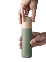 Peugeot | Boreal Pepper Mill, Fern Green, featuring a wooden top and adjustable metal knob, held in hands for use, reflecting a natural, streamlined design.