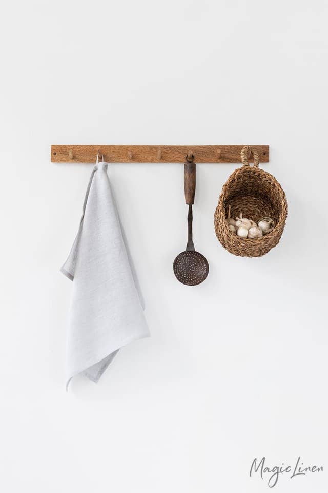Linen tea towel on a rack with utensils; absorbent, durable, European flax, ideal for kitchen use. Perfect for maintaining a neat kitchen.