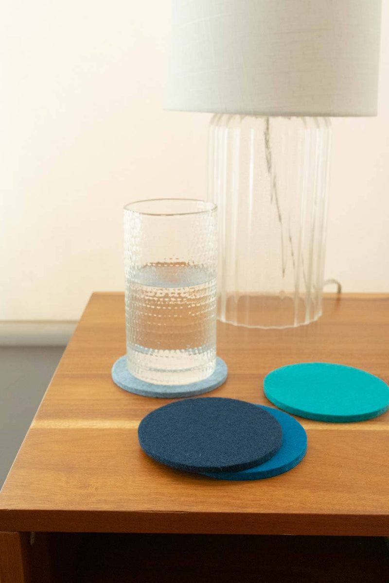 Graf Lantz - Bierfilzl Merino Wool Felt Round Coaster Multi 4 Pack: Ocean, shown next to a glass of water on a table.