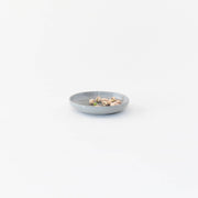 Sarah Kersten's Olive Dish from the Basin Collection holds pistachios. This small, versatile dish is perfect for various table settings. Diameter: 6, Height: 1.25.
