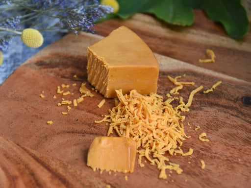 Rebel Cheese - Smoked Cheddar Plant Based, 5 oz on a wooden board, showcasing its firm texture ideal for slicing or shredding.