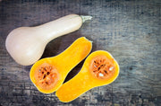 Heirloom Butternut Squash, Bentley Seed Co. - Squash-Butternut Waltham 1939, on rustic surface, whole and halved, showcasing vibrant orange flesh, ideal for soups and casseroles.