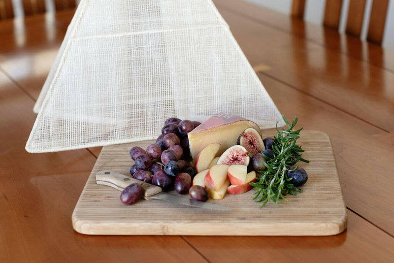NEEPA HUT | Collapsible Woven Food Tent - Rose Pink, elegantly covering fruit on a table, showcasing its unique pentagon shape and handmade craftsmanship.