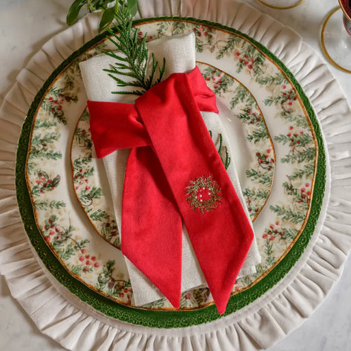 Arte Italica & Crown Linen Designs Napkin Sash Mini Wreath Velvet Red, elegantly adorns a holiday table setting with china and evergreen sprig, enhancing festive decor.
