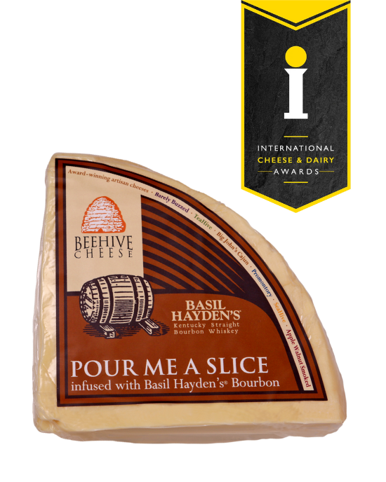 Beehive Cheese Co. LLC | Pour Me A Slice - 4 oz Wedge infused with Basil Hayden Bourbon, showcasing a close-up of the cheese with its artisanal label.
