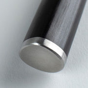 Close-up of Shun Classic Paring Knife, 4 inches, showcasing its dark cylindrical shaft with a brushed-aluminum end cap, highlighting precision craftsmanship.