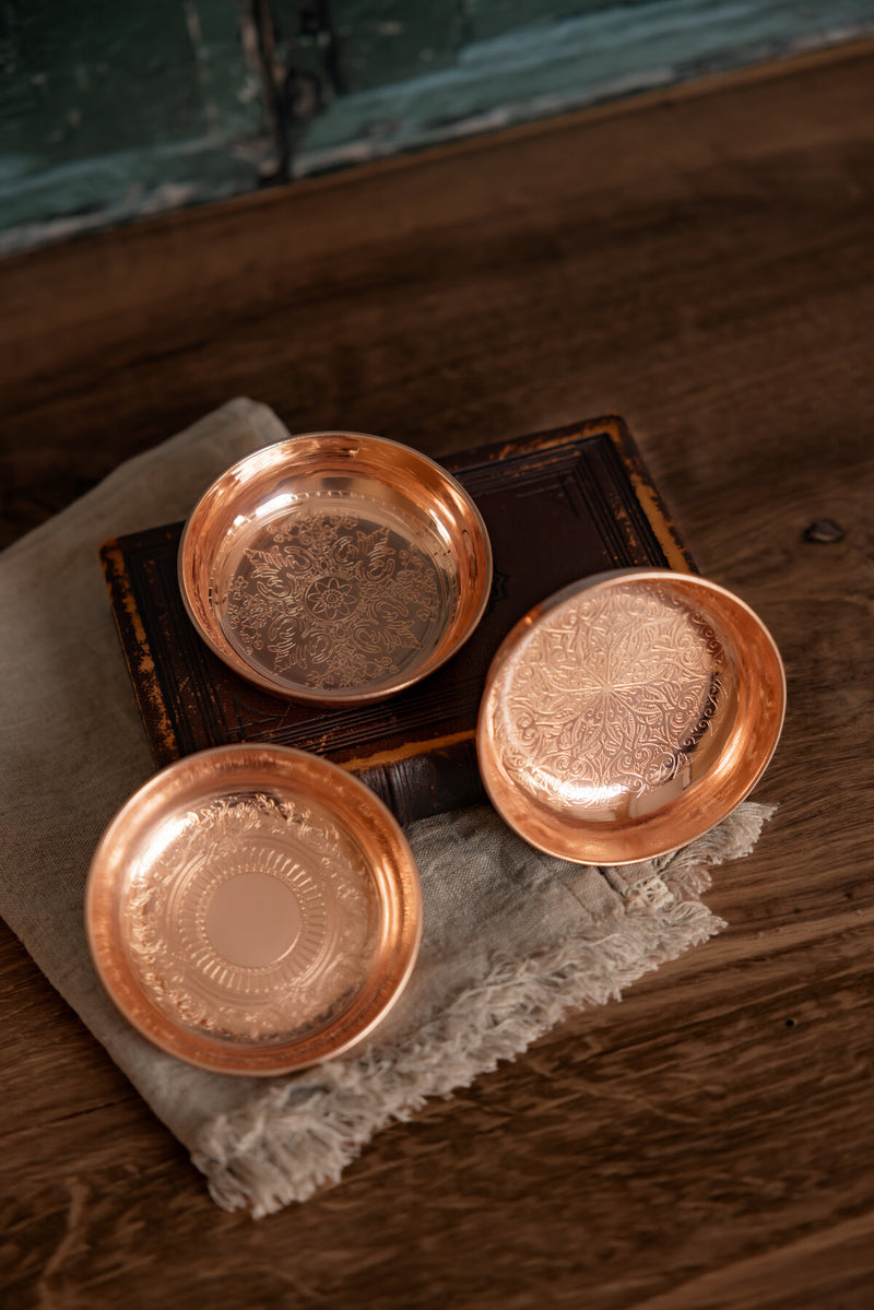 Vintage Inspired Ring Dish Rosette by Coppermill Kitchen: Three copper dishes with unique floral patterns on a rustic linen and wood backdrop. Perfect for kitchen or vanity use.