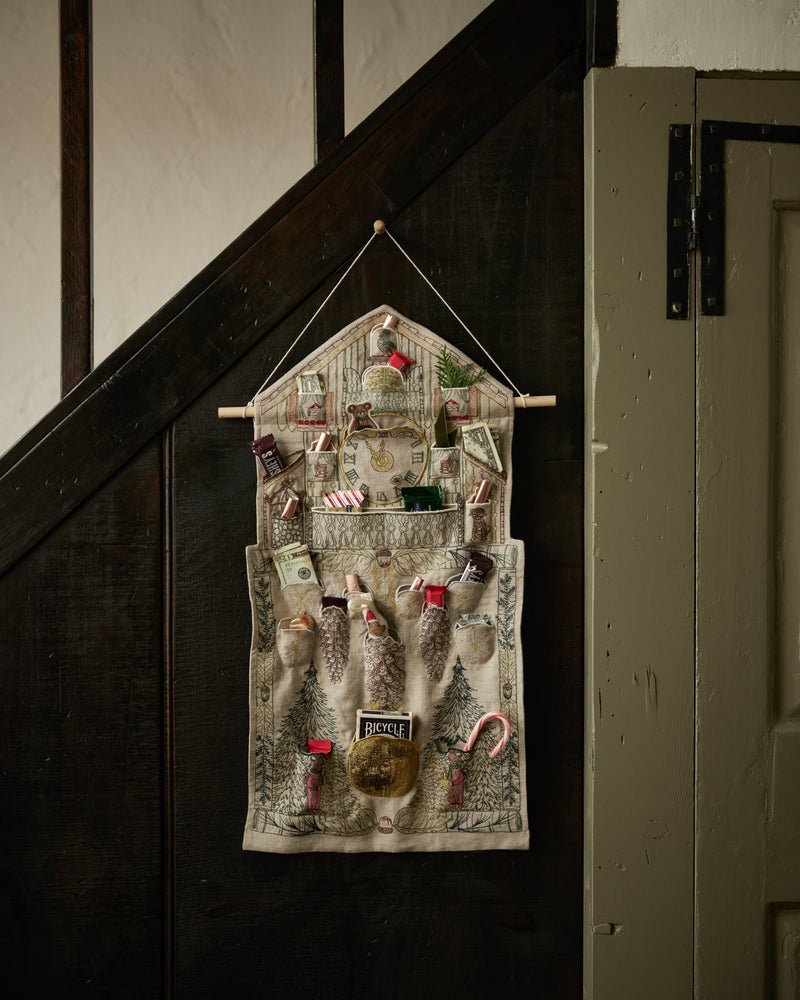Coral & Tusk | Christmas Clock Advent Calendar: Hanging fabric organizer with vintage clock design, filled with treats and surprises in 25 pockets, suspended from a wooden dowel.