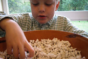 Boy enjoying a bowl of Rancho Gordo | Crimson Popping Corn, showcasing its appeal as a versatile snack, perfect for traditional or air-popped preparation.
