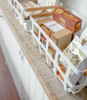 Yamazaki Home | Steel + Wood Storage Baskets, Large, holding gourmet packaged foods on a rustic shelf, ideal for organized kitchen storage.