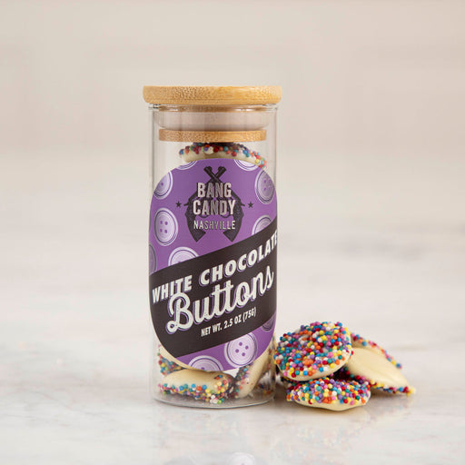 Hester & Cook | Buttons - White Chocolate in a clear jar with wooden lid, featuring rainbow-sprinkled, sea-salted chocolate buttons, ideal for snacking or gifting.