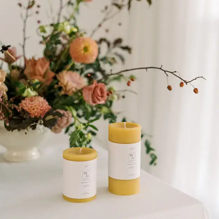 Mo&Co Home - 100% Beeswax Pillar Candles, hand-poured and unscented, set with fresh floral arrangement, showcasing natural elegance for home decor or special occasions.