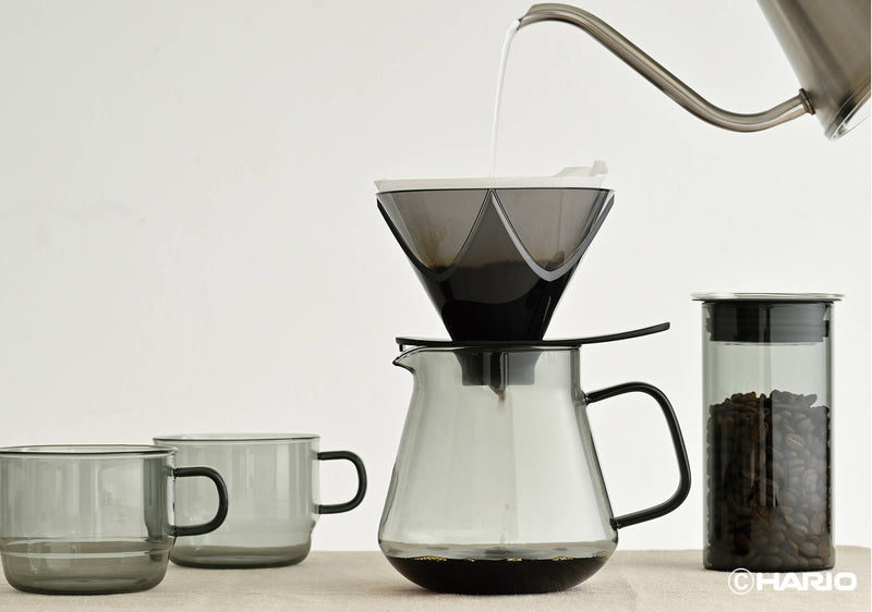 HARIO USA - HARIO Colors Glass Coffee and Tea Server, 600ml: Grey, featuring a pour-over setup with glass mugs, carafe, dripper, kettle, and coffee bean canister.