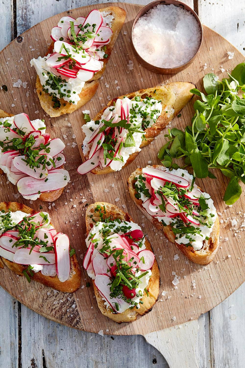 Overhead view of crostini with cheese and radishes, featuring Wholesome Good - Maldon Sea Salt 8.5oz / 12: Single, alongside a bowl of flaky sea salt.