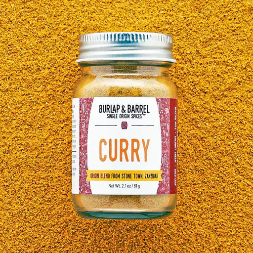 Burlap & Barrel - Curry - Single Origin Spice Blend: 2.1 oz glass jar set on loose curry powder, sourced from Zanzibar's smallholder farmers.