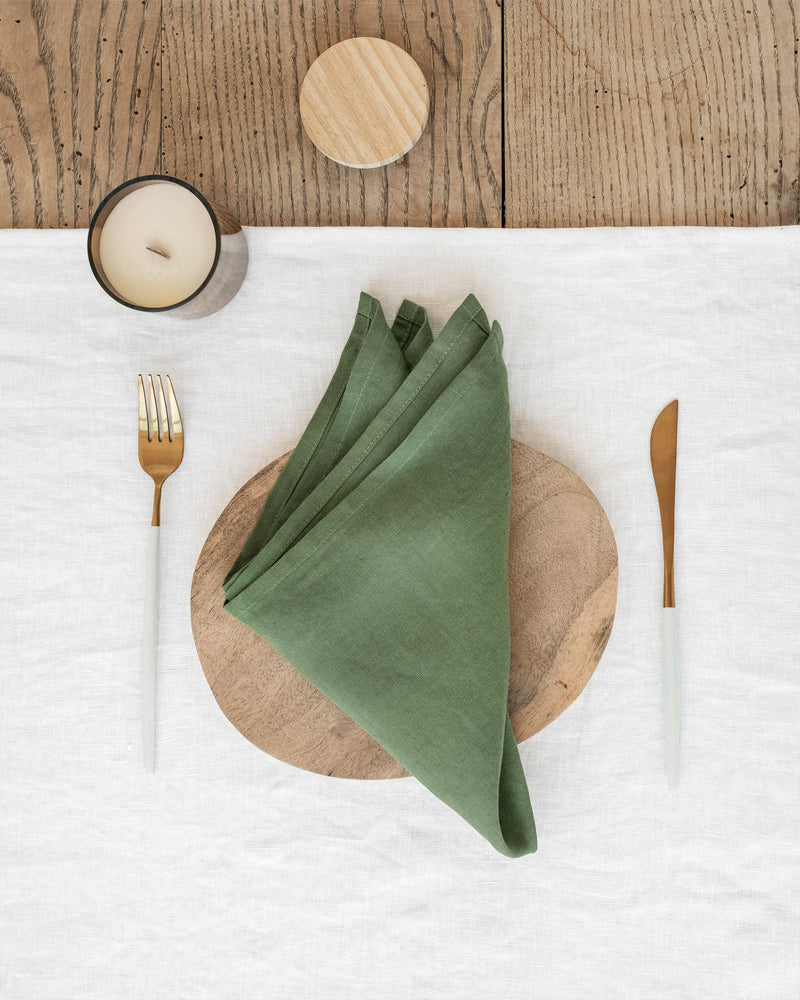 MagicLinen - Set of 2 pure linen napkins on a wooden plate, featuring a candle, ideal for stylish table decor.