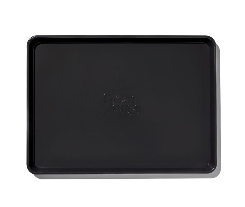 Great Jones | Holy Sheet - Blueberry: Black rectangular tray with logo, featuring nonstick ceramic coating for easy cleanup, ideal for kitchen and table use.